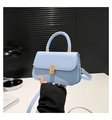 Close-up of light blue leather handbag featuring a golden rectangular twist lock and top handle - Blue