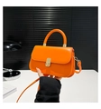 Macro view of bright orange mini flap handbag featuring gold twist lock and top handle - Orange