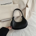 Bolso de media luna negro mate con detalles dorados sobre fondo minimalista - Negro