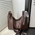 Dark brown faux leather tote bag with lace bow decoration in minimalist interior setting - Brown