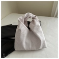 Close-up of woven leather texture and signature knot detail on a pale pink shoulder bag - White