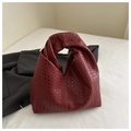 Macro shot of burgundy woven leather texture and knotted handle detail on hobo bag - Red
