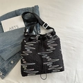 Black quilted tote bag with colorful wave embroidery and adjustable strap in lifestyle setting - Black