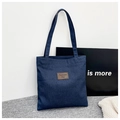 Detailopname van donkerblauwe denim shopper met bruin leren label en gestikte texturen - Stijl 2 (Leren Patch)