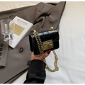 Close-up of black glossy mini chain bag featuring a gold square buckle and metallic strap - Black