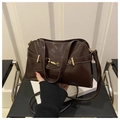 Detail of glossy brown leather crossbody bag with gold buckle on white props - Coffee