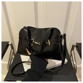 Detailed close-up of glossy black patent leather tote bag with elegant gold metal hardware - Black