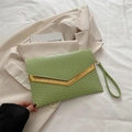 Bolso sobre verde claro con textura ondulada y detalle metálico dorado en forma de V - Verde
