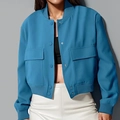 Detalle de chaqueta corta azul con bolsillos de solapa frontales y cuello de punto acanalado - Verde azulado