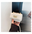 Detailed close-up of white chevron quilted bag with golden twist lock and chain strap - White