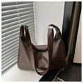 Close-up of large brown faux leather dumpling bag with textured surface and wide strap - Coffee