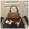 Detail of dark brown leather handbag with gold bow buckle and knotted handle design - Coffee