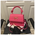 Close-up of fuchsia matte leather bag featuring a metal bow and knot handle detail - Rose Pink