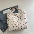 White corduroy tote bag featuring red strawberry prints and a front snap pocket - White
