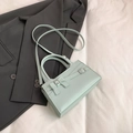 Bolso bandolera verde menta con lazo decorativo y hebilla de metal sobre una chaqueta - Azul