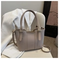 Detail view of a beige leather bucket bag on a chair with visible stitching and handle - Khaki