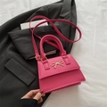 Mini borsa a tracolla rosa acceso con fiocco dorato su giacca grigio scuro - rosa acceso