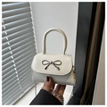 Macro shot of a white mini handbag featuring a silver metal bow and fine metal chain strap - White