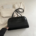 Borsa bowling nera lucida con doppi manici sottili su uno sfondo minimalista color crema - Nero