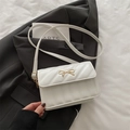 Elegant white quilted crossbody bag with golden bow clasp on grey blazer background - White