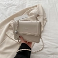 Beige crossbodytas met golvende rand, kiezel leerlook en goudkleurige metalen bal aan ketting - Wit