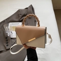 Elegante bolso bicolor crema y camello con asa trenzada y cierre metálico dorado - Caqui