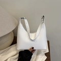 Minimalist white leather underarm shoulder bag with adjustable silver buckle on wood table - White