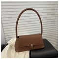 Détail de la texture tressée marron et du fermoir métallique sur le sac baguette chic - Beige