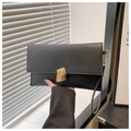 Detail of black textured envelope clutch with gold geometric clasp and wrist strap - Black