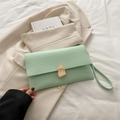 Pochette a busta verde menta testurizzata con chiusura dorata su giacca beige - Verde