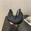 French woven crescent hobo bag in black leather texture shown against a minimalist wall - Black