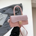 Light pink crossbody bag with glitter flap and gold twist lock in hand of a model - Pink
