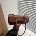 Brown patent leather shoulder bag with gold lettering shown in a stylish setting - Brown