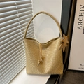 Geflochtene Tasche in Champagnergold mit Sternanhänger auf hellem Fensterbrett unter Licht - Khaki