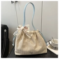 Dettaglio della borsa in paglia beige con fiocco in pizzo floreale e manici blu chiaro - Blu