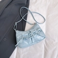 Light blue crossbody bag with bow accents and dual flap pockets on a grey suit background - Blue