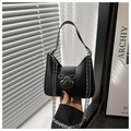 Detail of a black handbag featuring a silver metal bow buckle and elegant chain strap - Black