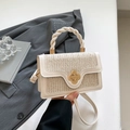 Sac à main tissé beige avec fermoir fleuri doré et poignée torsadée porté par modèle - Blanc