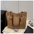 Detalle de bolso tote de paja con textura tejida marrón y asa de cadena plateada fina - Marrón