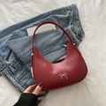 Red moon-shaped hobo bag with silver bow ornament on blue denim background - Red