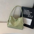 Bolso tote minimalista de charol verde claro con nudos de cordón sobre mesa blanca - Verde