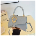 Detail showing glittery patchwork flap and large gold flower clasp on luxury handbag - Silver