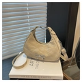 Macro shot of beige crescent tote bag with crinkled texture and silver bow charm - Khaki
