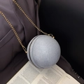 Spherical evening bag with silver glitter finish and gold chain on a book and blazer - Silver