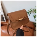 Detailed shot of brown leather crossbody bag featuring vintage gold triple-ring metal buckle - Brown