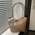 Bolso tote minimalista de cuero caqui con lazo de encaje y letras doradas con luz natural - Caqui