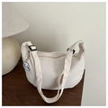 Detail of cream waffle texture shoulder bag with cute cloud pendant on wooden table - White