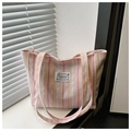 Detail of colorful striped canvas tote bag with fashion label on a sunlit windowsill - Pink