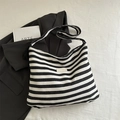 Striped black and cream canvas tote bag with a minimalist woven label shown on white surface - Black