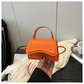 Dettaglio di una mini borsa a mano arancione brillante in pelle liscia con base a forma di onda - Arancione